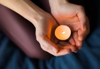 A selective focus closeup shot of female's hands holding a lit candle